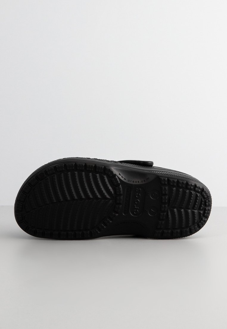 Zwarte schoeisel met een gestructureerde rubberen zool, met een gemodelleerd ontwerp met richels en logo's. Klittenbandsluiting en een ronde neusvorm.