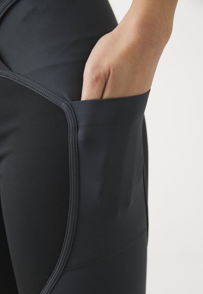 Svarte treningsleggings med en sidelomme. Materialet er glatt med en svakt glans, og synlige sømdetaljer fremhever designet.