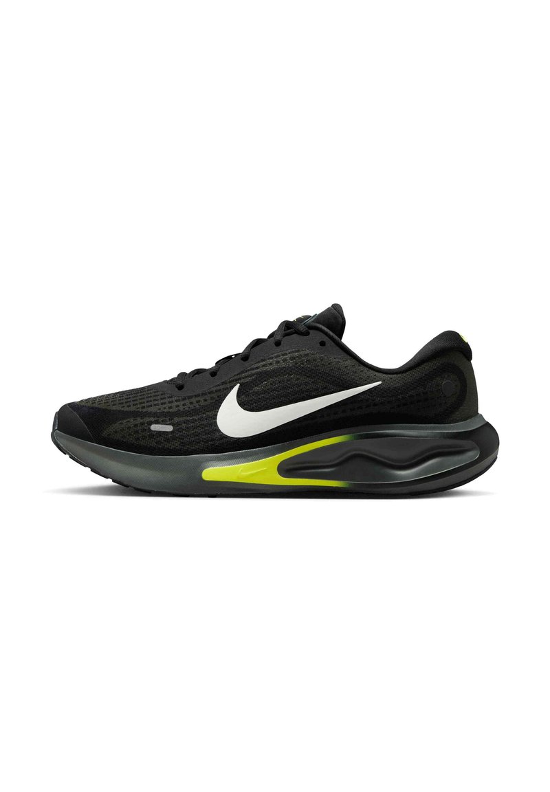 Czarne buty sportowe z siateczkową cholewką, białym logo Nike i zielonym akcentem na podeszwie. Lekka konstrukcja z teksturowanymi powierzchniami.