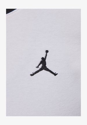 Bílá tkanina s ribbed texture a černě vyšívaným logem Jumpman, které je výrazně zobrazeno. Design zahrnuje kontrastní výstřih.