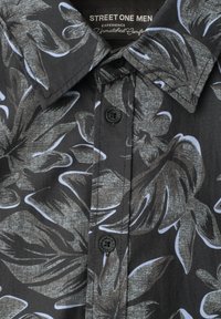 Chemise noire pour homme à boutons avec un grand imprimé de feuilles tropicales grises et blanches et un col pointu, étiquetée Street One Men.