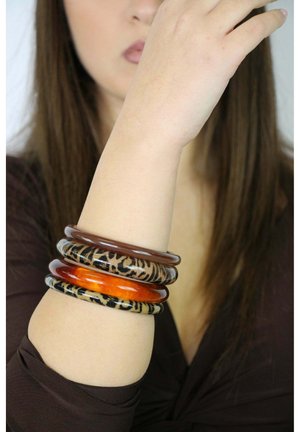 Four bracelets in varying colors: two amber, one black with a leopard pattern, and one brown. Smooth, glossy material with round shapes.