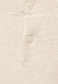 Světle béžový pletený svetr s žebrovaným límcem, obsahující tři malé kulaté krémové knoflíky a měkkou, texturovanou tkaninu.