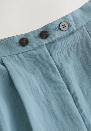 Helles blaues Stoffbund mit zwei dunklen Knöpfen, ausgestattet mit strukturierten Falten für zusätzlichen Detail. 