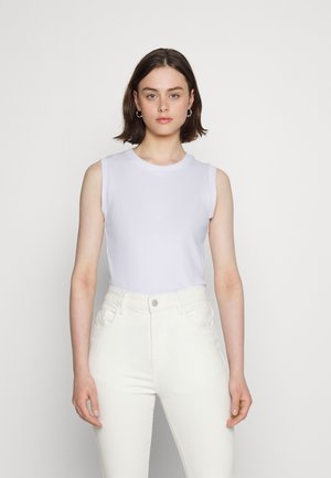 Top branco sem mangas com um decote redondo, combinado com jeans brancos de cintura alta. Tecido suave com uma silhueta ajustada. Design simples e minimalista.