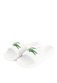 Infradito bianchi con suola testurizzata e fasce larghe. Ogni fascia presenta un logo di coccodrillo verde. Materiale sintetico liscio.