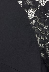 Vestido preto com um tecido suave e um painel de renda floral. A renda texturizada contrasta com o material sólido, destacando o design.