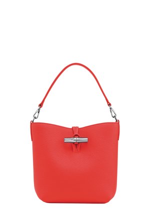 Red textured leather handbag with a single rounded handle and a prominent metallic clasp at the front. Smooth finish, minimalist design.