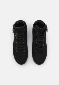 Černé vysoké tenisky vyrobené z semiše s hladkým povrchem, se šněrováním v přední části a bočním zipem. Plochá gumová podrážka.