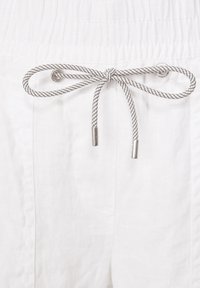 Pantaloni bianchi di lino con tessuto strutturato, vita elasticizzata e un cordoncino grigio e bianco con punte metalliche.