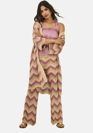 Conjunto de tres piezas de punto con patrón de zigzag; colores rosa claro y beige; incluye una camiseta sin mangas, pantalones anchos y un chal.