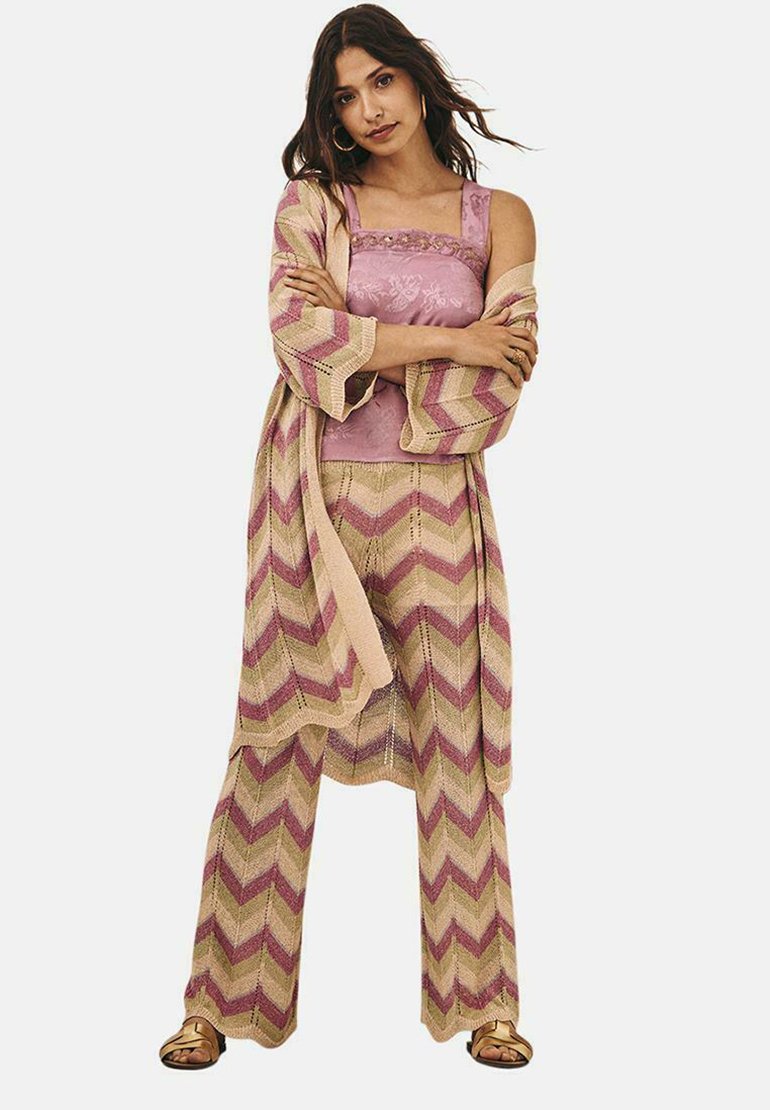 Conjunto de tres piezas de punto con patrón de zigzag; colores rosa claro y beige; incluye una camiseta sin mangas, pantalones anchos y un chal.