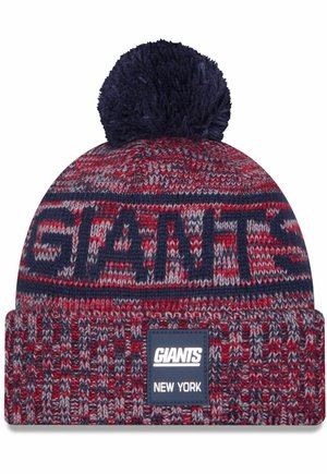 Bonnet tricoté rouge, marine et gris avec un pom-pom sur le dessus. Présente "GIANTS" en grandes lettres et un patch logo étiqueté "NEW YORK."