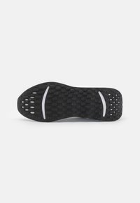 Black shoe sole with textured surface and numerous small circular patterns. Features two white stripes for design and grip.
