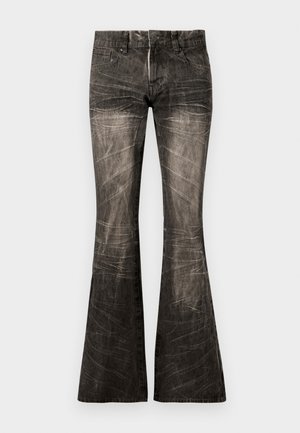 Kitsaste mustad teksad, millel on kulunud viimistlus, nupuga ja tõmblukuga sulgemine, eesmine tasku ning eristuvad vertikaalsed jooned kangal.