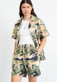 Set de cămașă cu mânecă scurtă și pantaloni scurți în imprimeu cu palme de culoare verde, bej și negru. Material ușor, croi lejer și talie elastică la pantaloni.