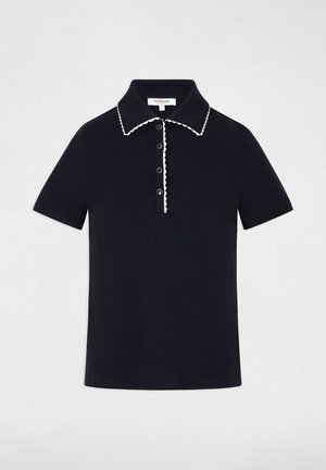 Polo nera a maniche corte con rifiniture bianche smerlate lungo il colletto e la patta dei bottoni, con quattro bottoni neri sul davanti.