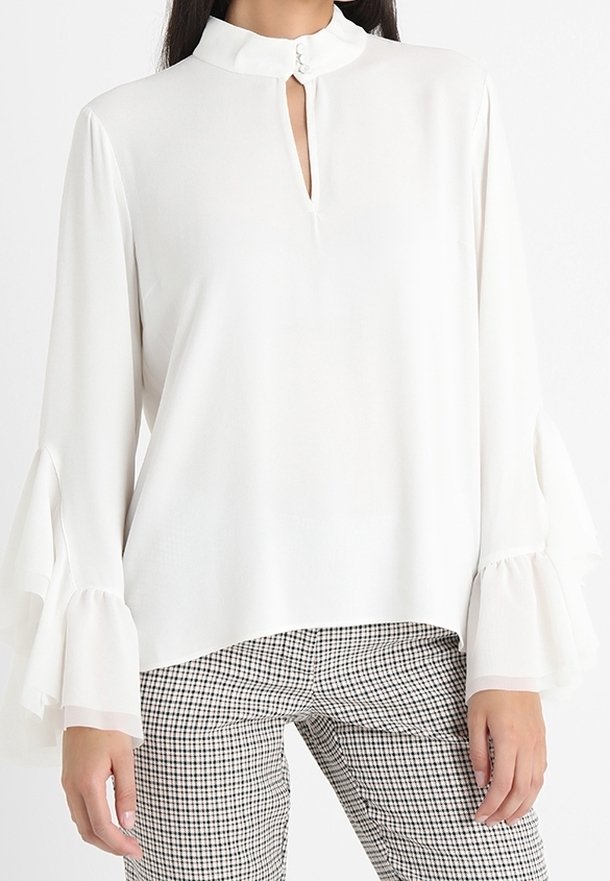 Blusa bianca a maniche lunghe con colletto alto e scollatura a chiave. Presenta maniche a campana e un tessuto liscio e leggero.