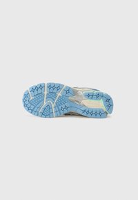 Semelle en caoutchouc bleue avec un motif de semelle hexagonal, présentant des accents argentés. Le design comprend des rainures pour la flexibilité et la traction.