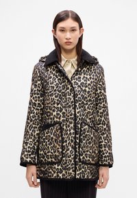 Kabát prošívaný s leopardím vzorem, černým límcem, předními kapsami a zapínáním na zip. Látka má lesklý, strukturovaný povrch.