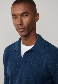 Gebreide pullover in donkerblauw met gespikkelde accenten van geel en blauw, gekenmerkt door een kraag en een gestructureerde, textuurstof.