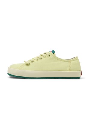 Light yellow canvas sneaker with round toe, green rubber sole, and six lacing holes. Features contrasting green heel tab and logo tag.