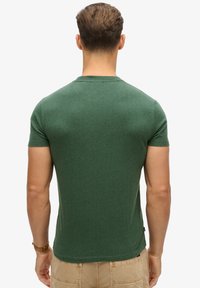 Donkergroene korte mouwen t-shirt van zachte stof, met een ronde halslijn en een getailleerd ontwerp, zonder zichtbare patronen of accenten.