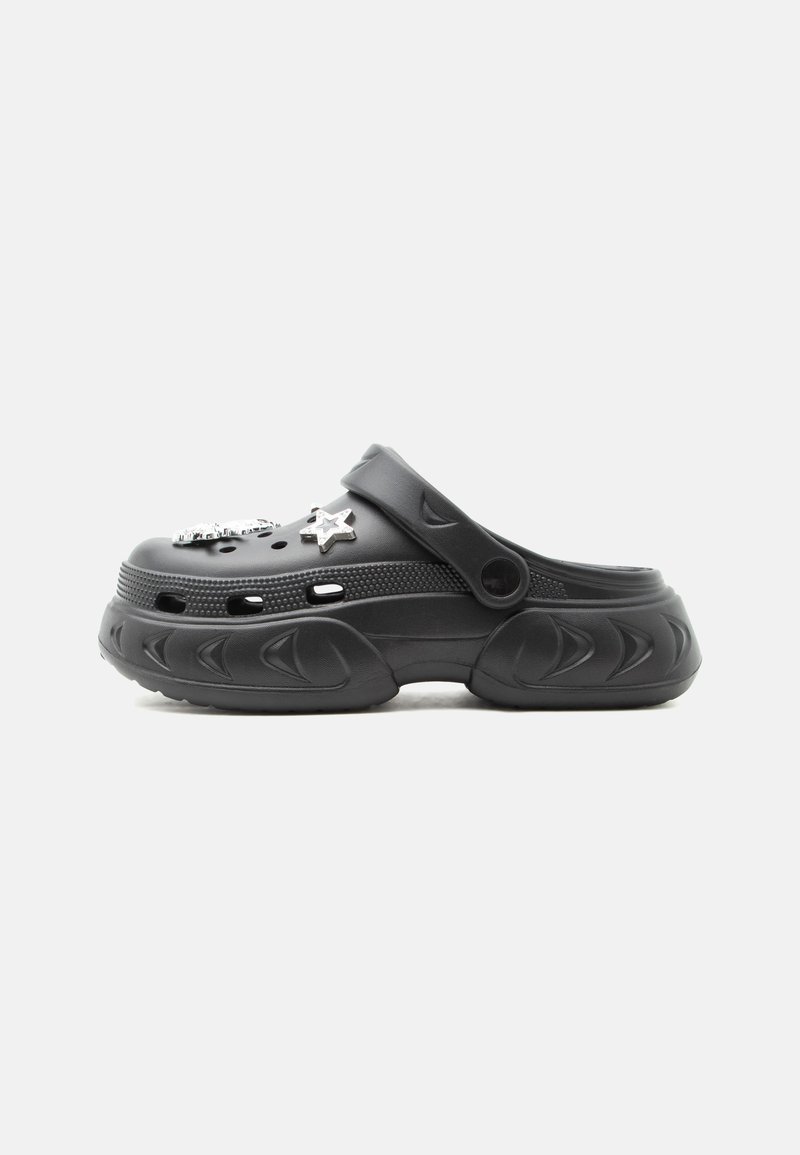 Μαύρο clog τύπου slip-on με παχιά σόλα, οπές αερισμού, ρυθμιζόμενο λουράκι στη φτέρνα και δύο ασημένια κρεμαστά σε σχήμα αστεριού στην κορυφή.