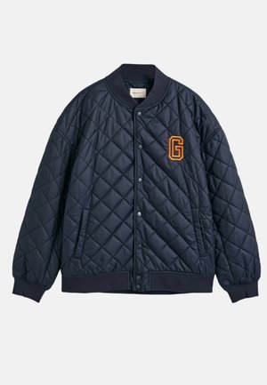 Granatowa pikowana kurtka bomberka z prążkowanym kołnierzem, zapięciem na zatrzaski, bocznymi kieszeniami oraz pomarańczowym logo "G" na lewej piersi.