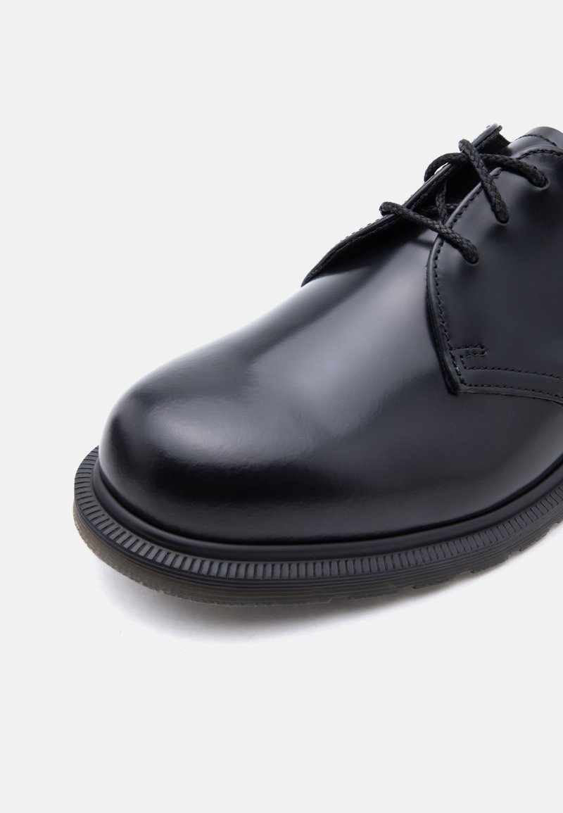 Schwarzer, polierter Leder-Schnürschuh mit abgerundeter Spitze und strukturiertem Gummisohlenprofil, aus der vorderen Seitenansicht gezeigt.