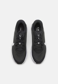 Zwarte mesh sport schoenen hebben een gestructureerde bovenkant, witte accenten, ronde veters en een gewatteerde zool, ontworpen voor comfort en prestaties.