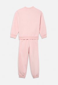 Rozā džemperu un sporta biksīšu komplekts no mīksta auduma. Ar ribotu aproču apdari un apaļu apkakli. Vienkāršs dizains, bez redzamiem rakstiem vai izteiksmīgiem elementiem.