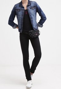 Džínová bunda, černý top s potiskem, černé skinny džíny, černá ledvinka s bílými puntíky a bílé tenisky.