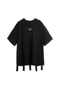 Camiseta negra de corte oversized, hecha de algodón, con un bolsillo rectangular que presenta un detalle de texto y tres tiras de tela en el dobladillo.