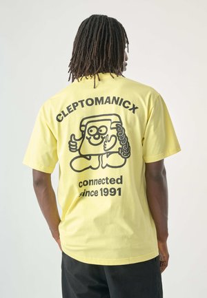Gelbes Baumwoll-T-Shirt mit einem großen schwarzen Motiv einer lächelnden Figur, die auf der Rückseite ein Telefon hält, sowie dem Text "CLEPTOMANICX connected since 1991."