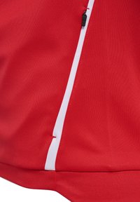 Red fabric with a vertical white stripe and a black zipper pull near the top right of the stripe.