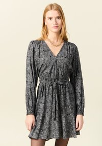 Schwarzes Langarmkleid mit floralem Muster, V-Ausschnitt, elastischem Taillenbund und einem Bindegürtel, vollendet mit einem ausgestellten Saum.