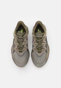 Olivgröna mocka- och mesh-sneakers med grå detaljer, texturerade snören och en vadderad sula, med en logotyp på tungan.