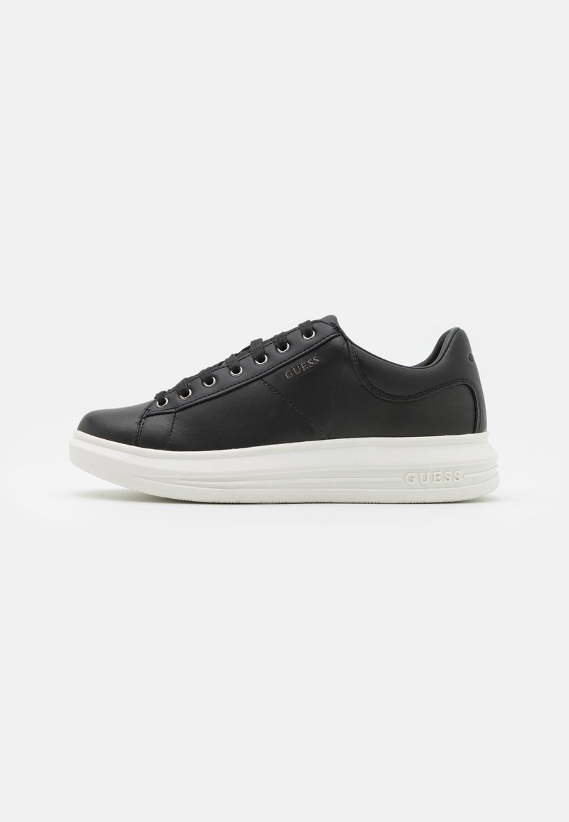 Black leather sneaker with a rounded toe, white rubber sole, six pairs of metal eyelets, and embossed logo on the side.