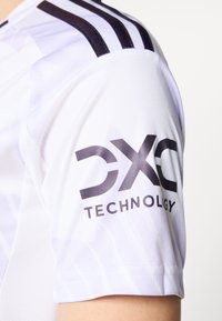 Bela športna majica z temnimi črtami na ramenih in izrazitim logotipom "DXC TECHNOLOGY" na rokavu.