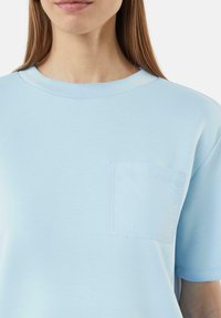 Lichtblauw katoen T-shirt met een ronde hals, korte mouwen en een klein borstzakje met een zachte, gladde textuur.