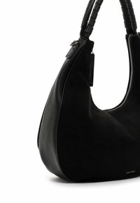 Black handbag made of leather and suede with a smooth texture, a curved shape, and a zipper closure; features a woven handle.