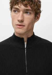 Czarny prążkowany sweter na zamek z wysokim kołnierzem i srebrnym suwakiem, zaprojektowany o dopasowanym kroju i teksturowanej tkaninie.