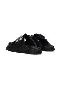 Zapatos negros de tela trenzada tipo slip-on con partes superiores texturizadas, que cuentan con hebillas decorativas y una suela gruesa negra. Diseño casual con parte trasera abierta.