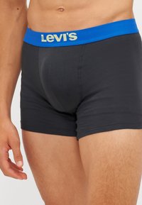 Boxers noirs en coton, avec une ceinture bleue portant le logo "Levi's" en doré. Le design assure un ajustement confortable.