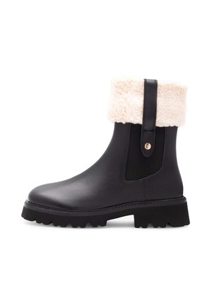 Black leather ankle boots with a white faux fur cuff, elastic side panels, and a chunky black rubber sole with textured tread.