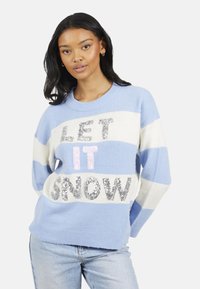 Lichtblauwe trui met witte en donkerblauwe strepen, versierd met glinsterende tekst "LET IT SNOW" in zilveren en roze pailletten. Gezellige gebreide textuur.