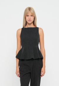 Sort peplum top med tætsiddende overdelen og rundet halsudskæring, lavet af tekstureret stof, parret med matchende mørke bukser.