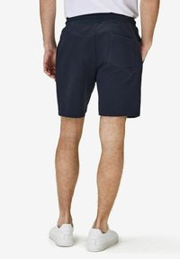 Marina blå shorts i mjukt tyg, med en bakficka, elastisk midja och rak passform, tillsammans med vita sneakers.