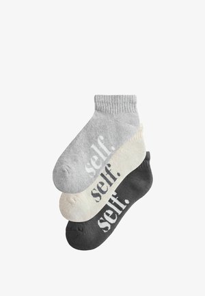 Three pairs of ankle socks stacked, in light gray, cream, and dark gray, each with the word "self." printed on the foot.